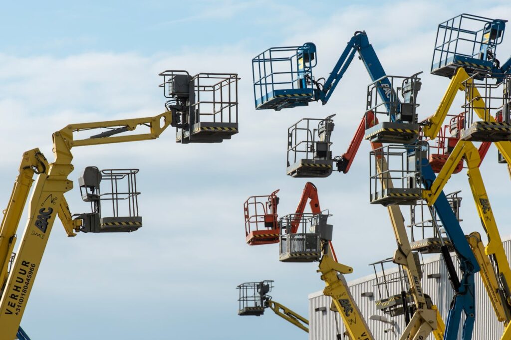 Crafting Captivating Headlines: Your awesome post title goes here A collection of colorful boom lifts reaching toward a clear blue sky, showcasing industrial machinery.